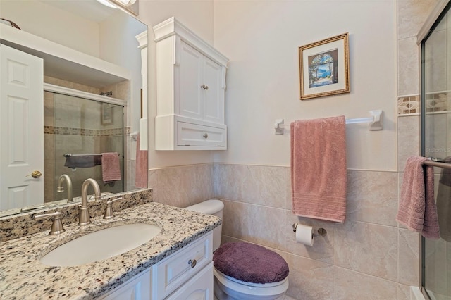 bathroom featuring walk in shower, vanity, toilet, and tile walls