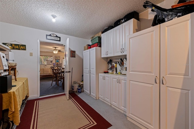 kitchen with white cabinets, a textured ceiling, and ceiling fan