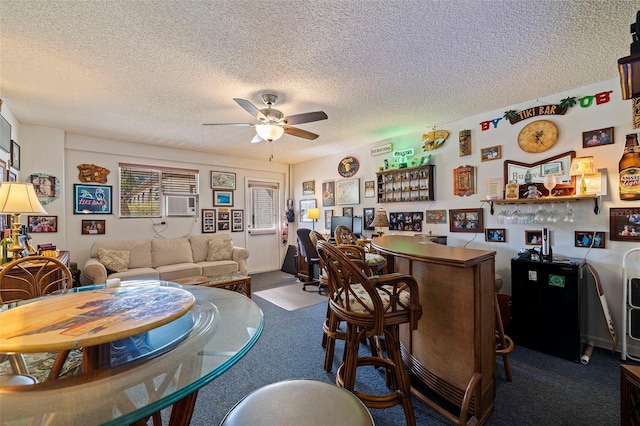 interior space with carpet flooring, bar area, a textured ceiling, and ceiling fan