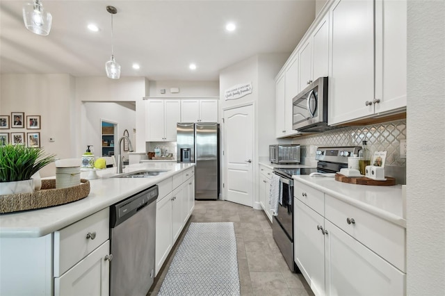 kitchen with decorative backsplash, stainless steel appliances, sink, decorative light fixtures, and white cabinetry