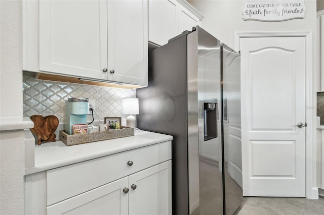 kitchen featuring white cabinets, decorative backsplash, and stainless steel refrigerator with ice dispenser