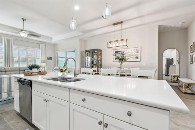 kitchen featuring dishwasher, a center island with sink, sink, decorative light fixtures, and white cabinetry