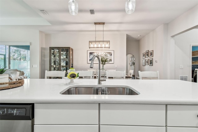 kitchen featuring dishwasher, white cabinets, hanging light fixtures, and sink