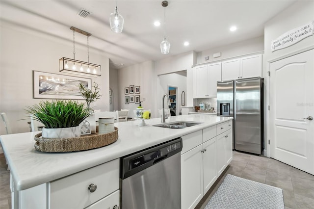 kitchen with stainless steel appliances, white cabinets, a center island with sink, and a sink