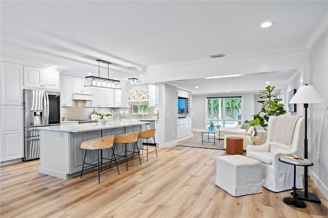 kitchen with white cabinets, appliances with stainless steel finishes, a center island, decorative light fixtures, and a breakfast bar