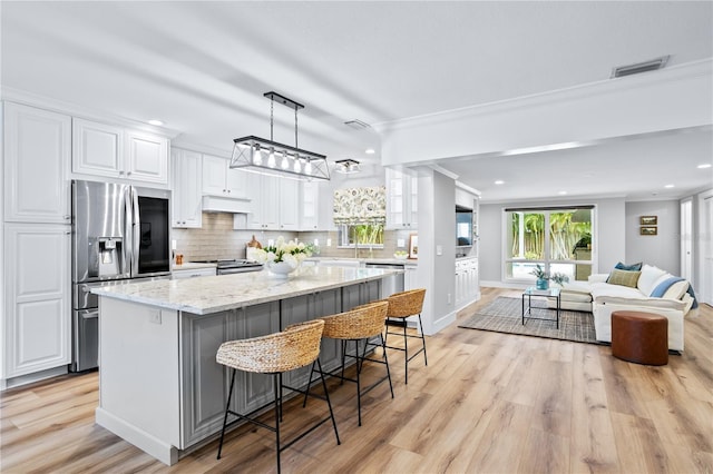 kitchen featuring white cabinets, a kitchen island, decorative light fixtures, a breakfast bar, and stainless steel appliances