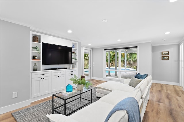 living room with built in shelves, light hardwood / wood-style flooring, and crown molding