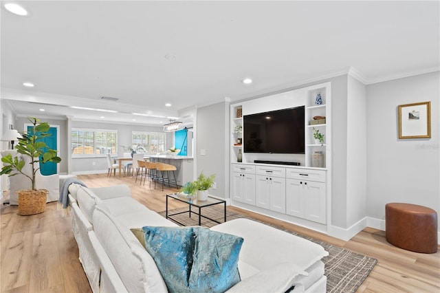 living room featuring built in shelves, ornamental molding, and light hardwood / wood-style floors