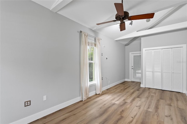 unfurnished bedroom featuring multiple windows, lofted ceiling with beams, a closet, and ceiling fan