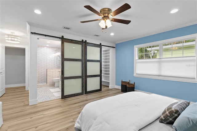 bedroom with ensuite bathroom, ceiling fan, light wood-type flooring, a barn door, and ornamental molding