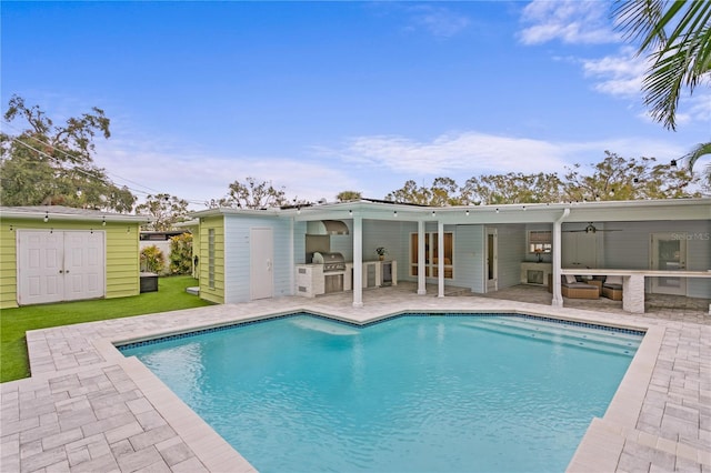 view of pool featuring exterior kitchen, a patio area, and ceiling fan