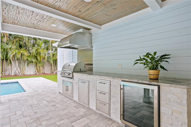 view of patio / terrace with grilling area, a fenced in pool, exterior kitchen, and wine cooler