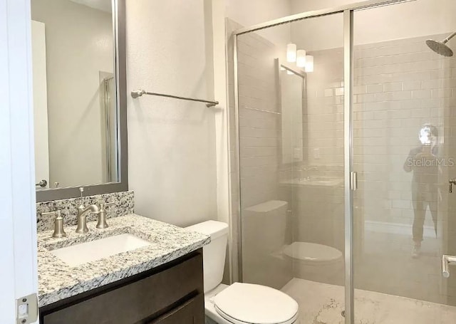 bathroom with vanity, a shower with shower door, and toilet