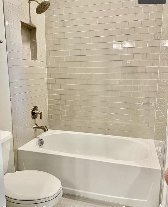 bathroom featuring toilet and tiled shower / bath