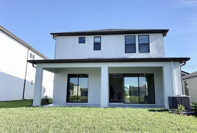 rear view of property featuring a lawn and central AC