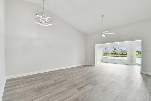 unfurnished living room featuring ceiling fan with notable chandelier, high vaulted ceiling, and light hardwood / wood-style flooring