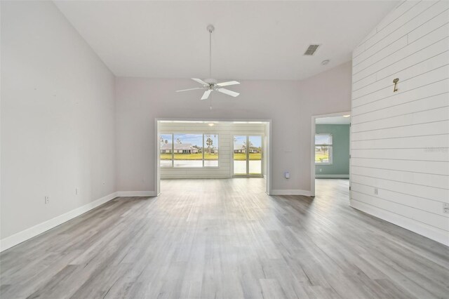 unfurnished living room with ceiling fan, light hardwood / wood-style flooring, and a high ceiling