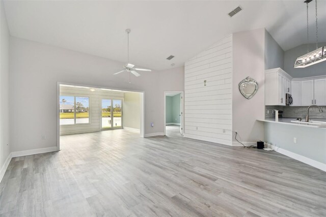 unfurnished living room featuring light hardwood / wood-style flooring, high vaulted ceiling, ceiling fan, and sink