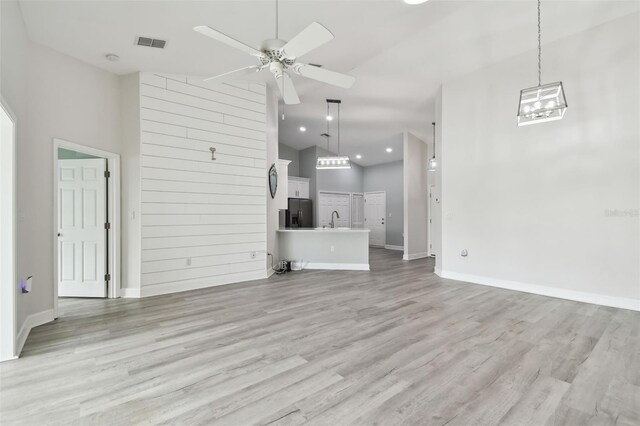 unfurnished living room featuring ceiling fan, sink, high vaulted ceiling, and light hardwood / wood-style flooring