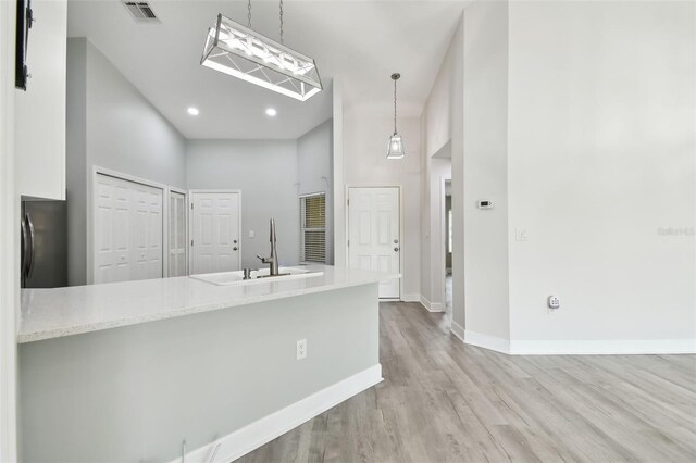 kitchen featuring kitchen peninsula, a towering ceiling, pendant lighting, and fridge