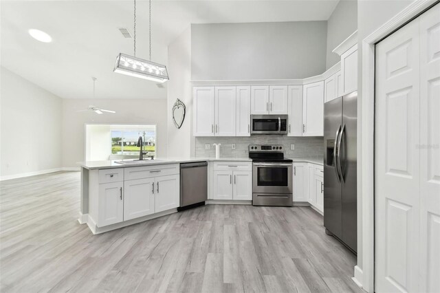 kitchen featuring kitchen peninsula, stainless steel appliances, white cabinets, and ceiling fan