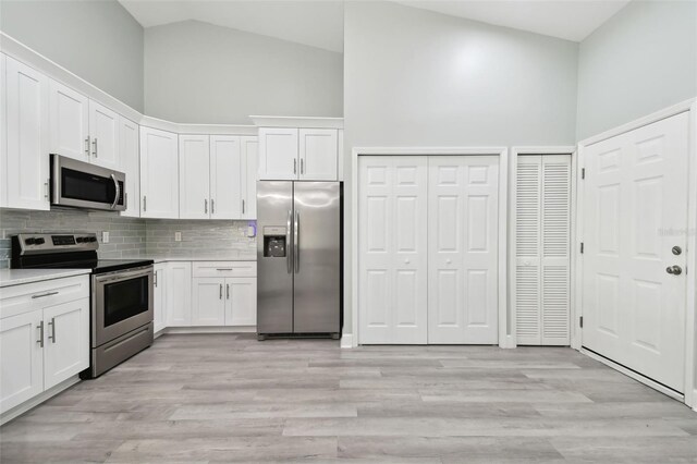 kitchen featuring decorative backsplash, stainless steel appliances, high vaulted ceiling, and white cabinetry