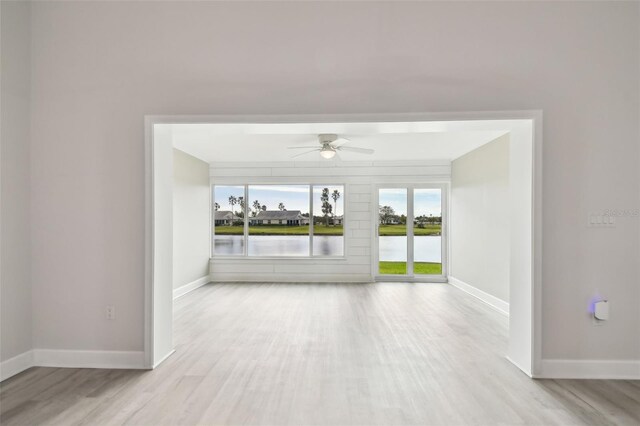 unfurnished room featuring a water view, light hardwood / wood-style flooring, and ceiling fan