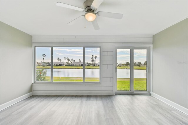 spare room featuring ceiling fan, a water view, and light wood-type flooring