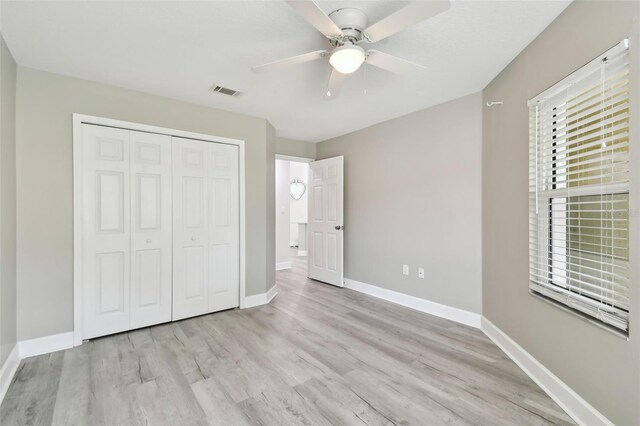 unfurnished bedroom with light wood-type flooring, a closet, and ceiling fan