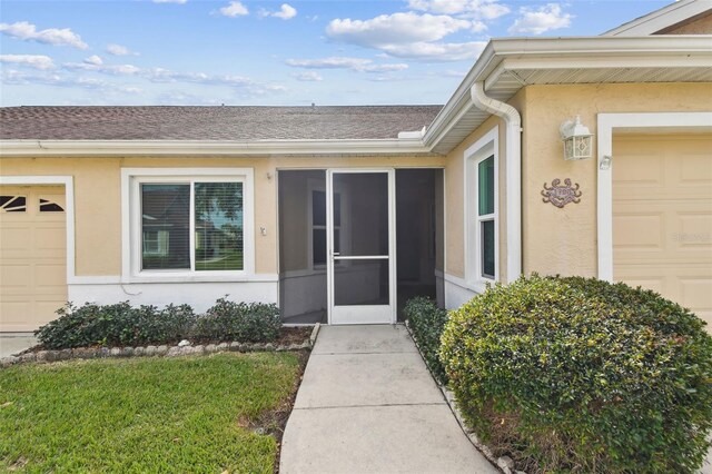 entrance to property featuring a lawn and a garage