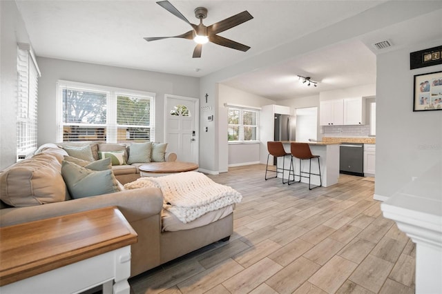 living room with ceiling fan, light hardwood / wood-style floors, and vaulted ceiling