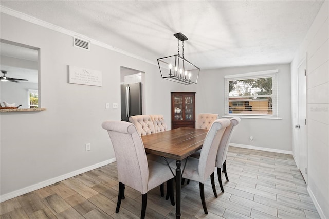 dining area with a wealth of natural light, crown molding, and ceiling fan with notable chandelier