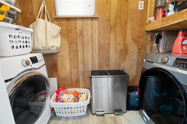 laundry area with wood walls, washing machine and dryer, and light hardwood / wood-style floors