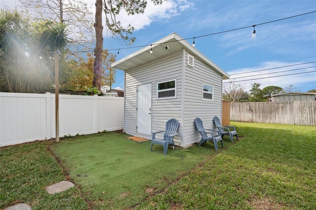 rear view of property with a yard and an outdoor structure