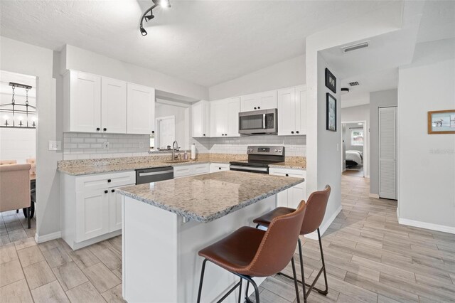 kitchen with white cabinets, stainless steel appliances, and a kitchen island