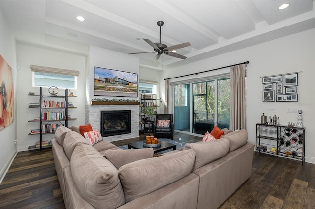 living room with dark hardwood / wood-style flooring, ceiling fan, a fireplace, and beamed ceiling