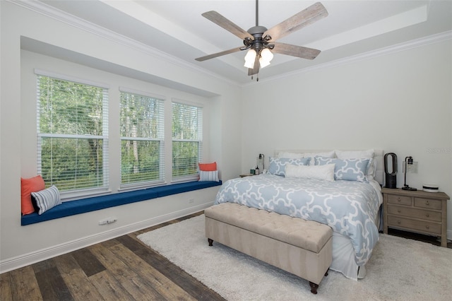 bedroom with hardwood / wood-style floors, ceiling fan, a raised ceiling, and multiple windows