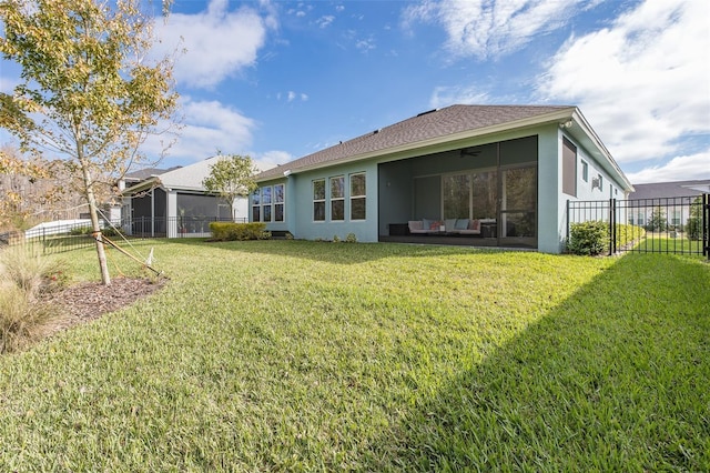 back of house with a sunroom, ceiling fan, and a yard