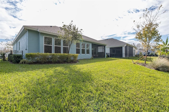 rear view of house with a yard and a sunroom