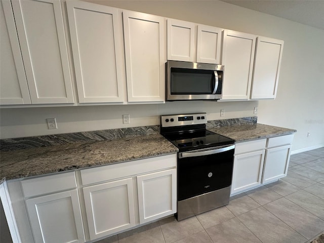 kitchen featuring stainless steel appliances, white cabinetry, and dark stone countertops