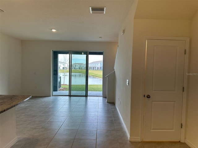 empty room featuring light tile patterned floors and a water view