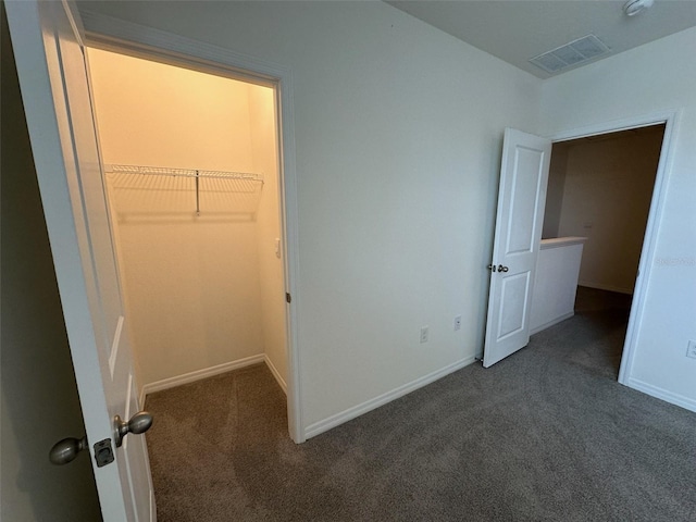 unfurnished bedroom featuring a spacious closet, a closet, and dark carpet