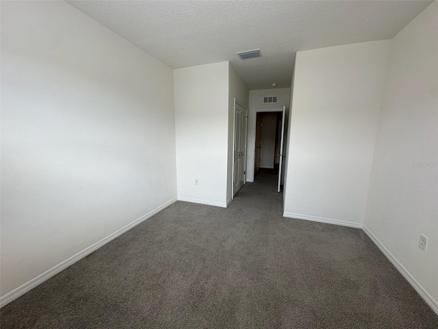 empty room with a textured ceiling and dark colored carpet