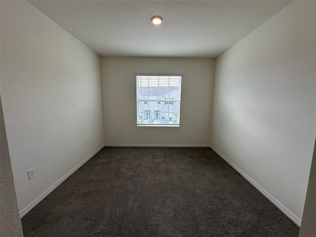 empty room featuring a textured ceiling and dark carpet