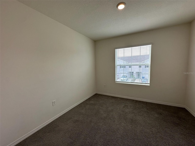 spare room with dark colored carpet and a textured ceiling