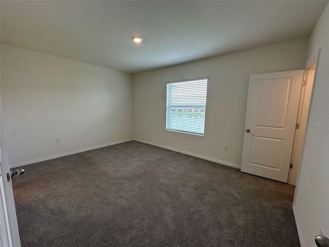 empty room with a textured ceiling and dark colored carpet