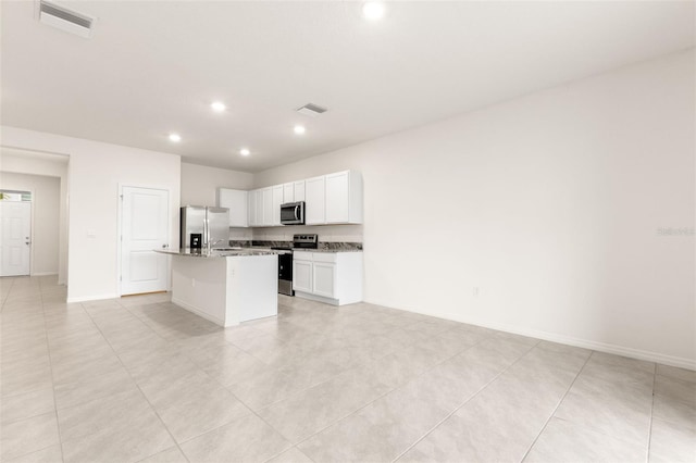 kitchen featuring a breakfast bar area, appliances with stainless steel finishes, white cabinetry, light stone counters, and a center island with sink