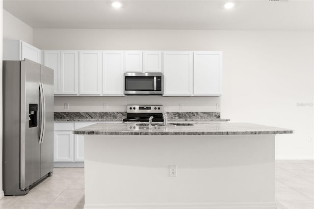 kitchen featuring appliances with stainless steel finishes, a center island with sink, white cabinets, and light stone counters