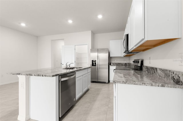 kitchen featuring appliances with stainless steel finishes, sink, white cabinets, a kitchen island with sink, and light stone counters