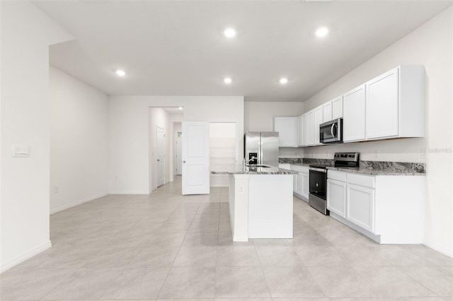 kitchen featuring appliances with stainless steel finishes, sink, white cabinets, a kitchen island with sink, and light stone counters